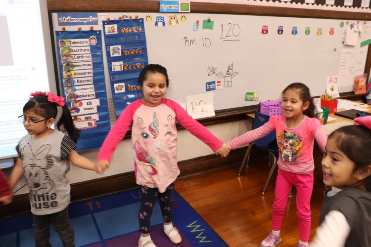 Kindergartners in Miss Sosa's class join hands. 