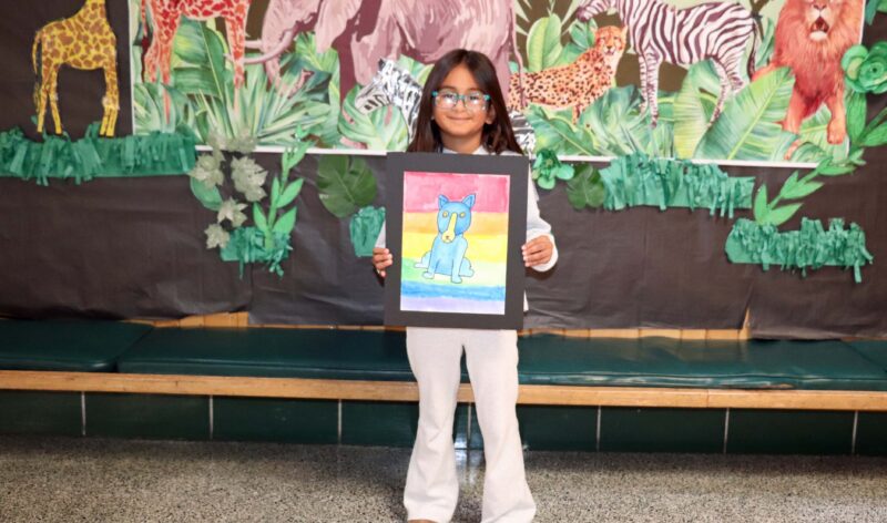 Noemi, a 4th grader, shows off her artwork entitled, "Blue Dog".