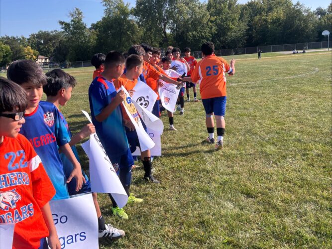 6th and 7th grade boys soccer players cheering for their 8th grade teammates